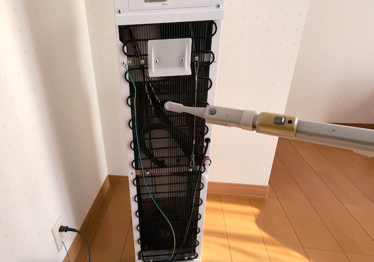 ハミングウォーターの背面のホコリをブラシノズル付きの掃除機で吸い取っているところ