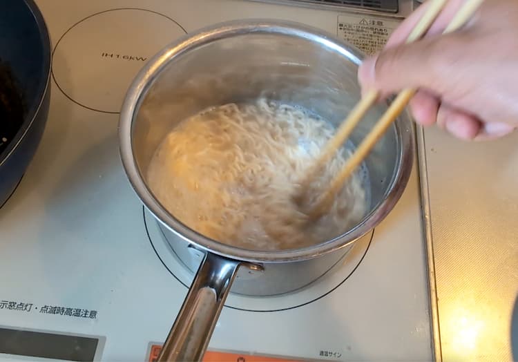 沸騰したお湯にインスタント麺を入れて混ぜているところ