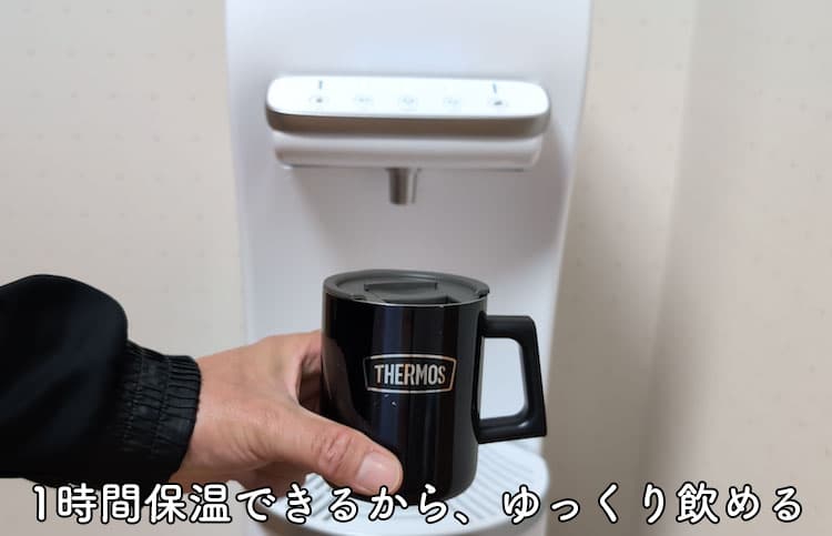 ハミングウォーターの温水と常温水を保温マグカップに注いで作った白湯を手に持っているところ