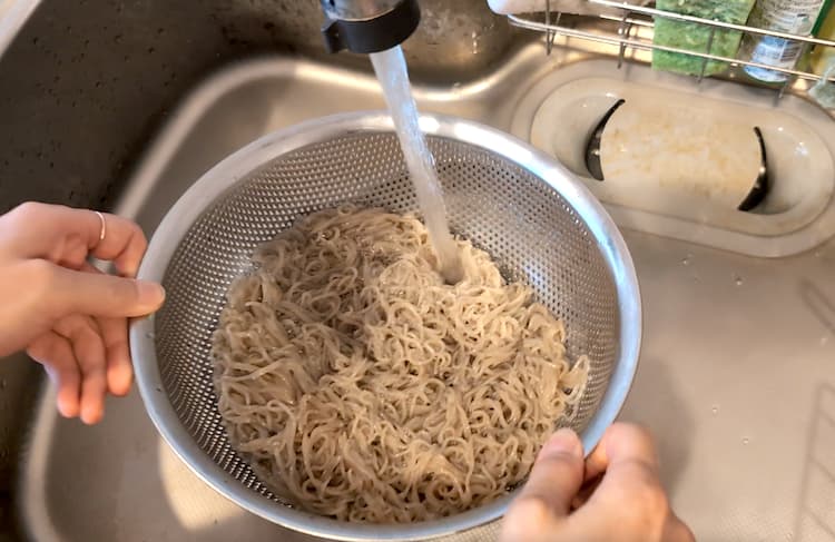 茹でた冷麺の麺を流水で洗っているところ