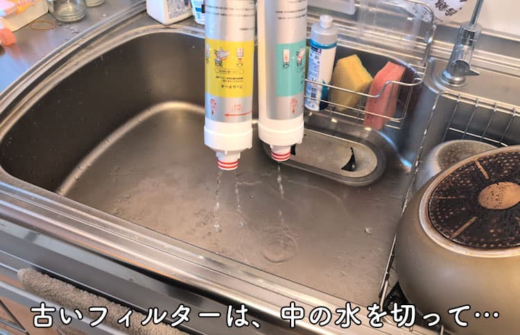 ハミングウォーターの古い浄水フィルターの中に入っている水を切っているところ